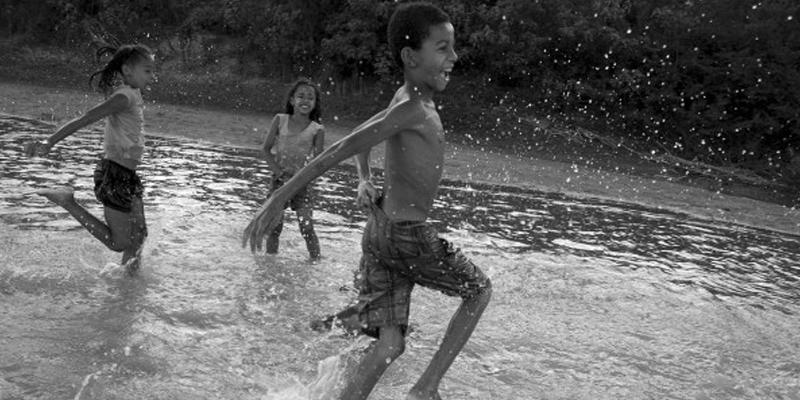 agua Foto em preto e branco de três crianças brincando no rio