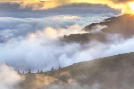 Foto do topo de uma montanha, acima das nuvens.