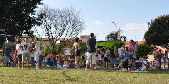 Foto com pessoas em uma quadra de vôlei ao céu aberto.