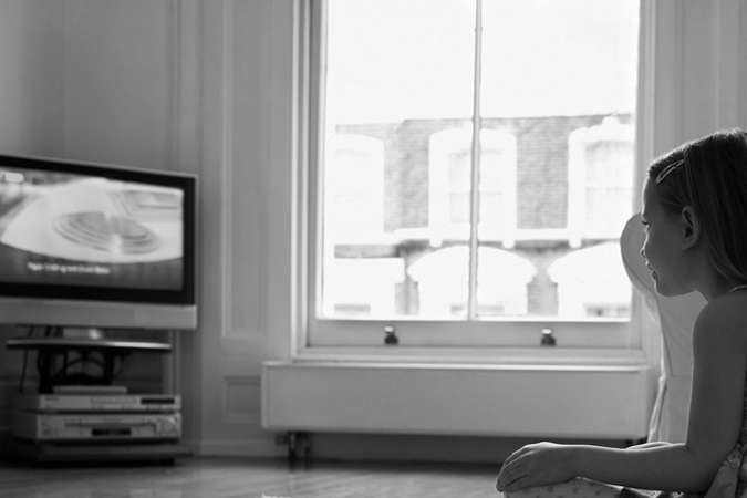 Foto em preto e branco de criança assistindo televisão
