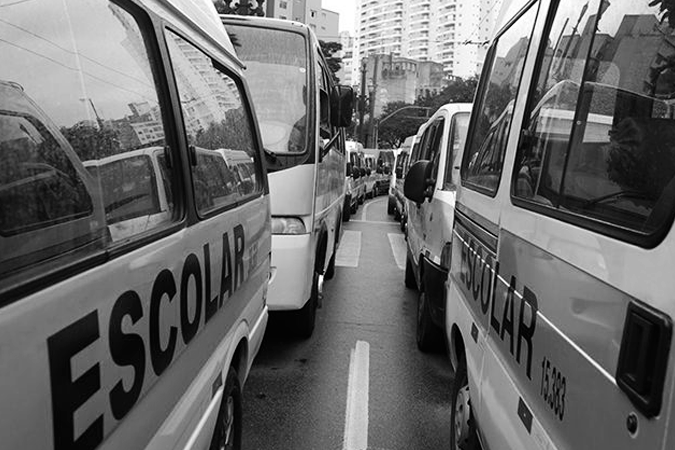 Foto em preto e branco de duas peruas escolares no transito