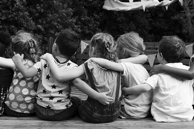 Foto em preto e branco de crianças de costas abraçadas