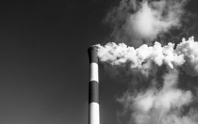 Foto em preto e branco de chaminé de fábrica industrial soltando uma fumaça branca