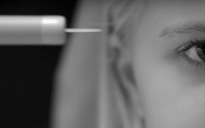foto em preto e branco da metade do rosto de uma menina, em frente uma agulha apontada para o lado esquerdo. Cena da série  Black Mirror
