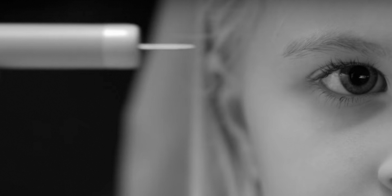 foto em preto e branco da metade do rosto de uma menina, em frente uma agulha apontada para o lado esquerdo. Cena da série  Black Mirror