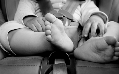 Foto em preto e branco de criança sentada em cadeirinha no carro