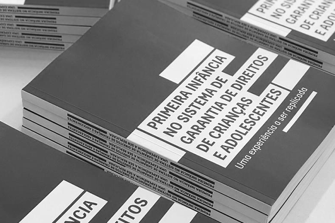 Foto mostra pilha de livros 'A primeira infância no sistema de garantia de direitos de crianças e adolescentes'