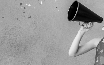 Foto em preto e branco de criança fantasiada de palhaça, para o carnaval, falando em megafone
