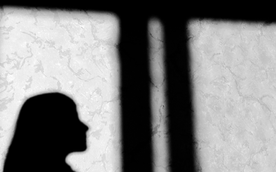 foto em preto e branco mostra sombra de mulher e de grades no sistema socioeducativo