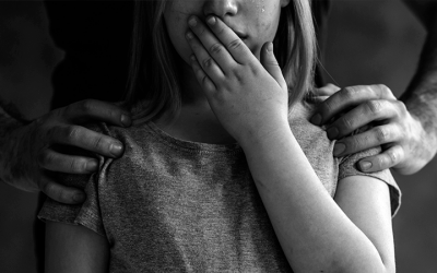 Foto em preto e branco mostra criança chorando com a mão na boca enquanto um homem segura seus ombros