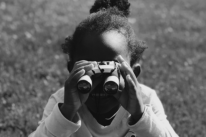 Foto em preto e branco de menina com binóculos