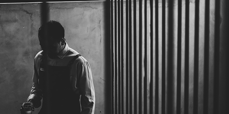 Notícias Foto em preto e branco de adolescente. À direita grades representando o sistema socioeducativo