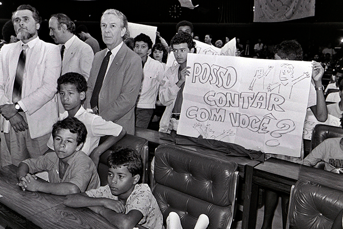 Foto em preto e branco mostra crianças do Movimento Nacional de Meninos e Meninas de Rua (MNMMR) ocupando o Congresso em sessão simbólica. Crianças seguram cartaz escrito: posso contar com você? | ECA