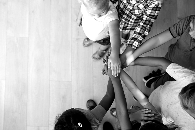 Foto em preto e branco vista de cima mostra várias crianças dando as mãos