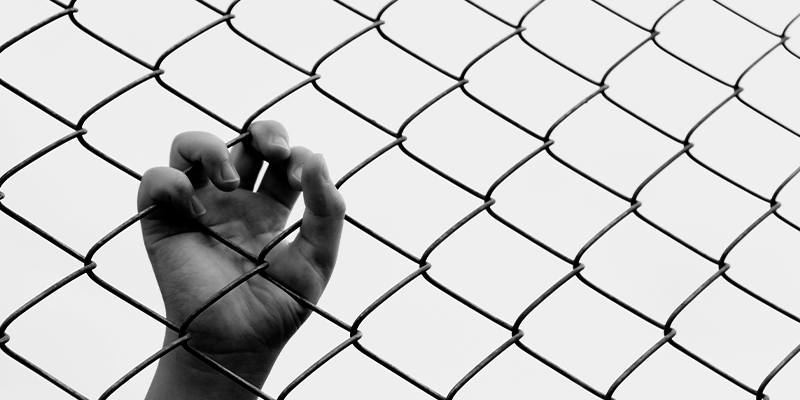 Notícias foto em preto e branco de mão de adolescente segurando grade