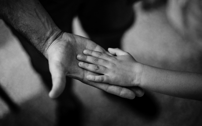 Foto em preto e branco mostra criança com a mão sobre a de adulto