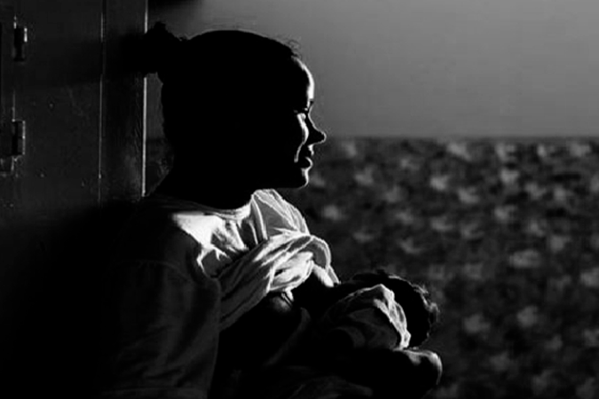 Foto em preto e branco mostra mãe em privação de liberdade amamentando bebê