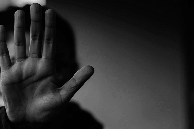 Foto em preto e branco mostra adolescente com a mão estendida em sinal de "pare", em referência a letalidade policial