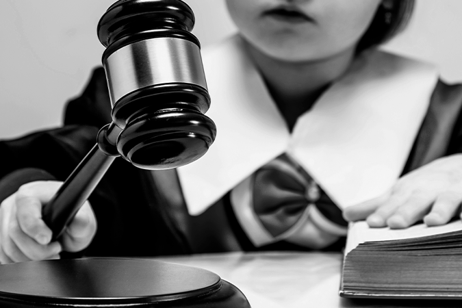 Foto em preto e branco mostra criança vestida de juiza com um martelo na mão