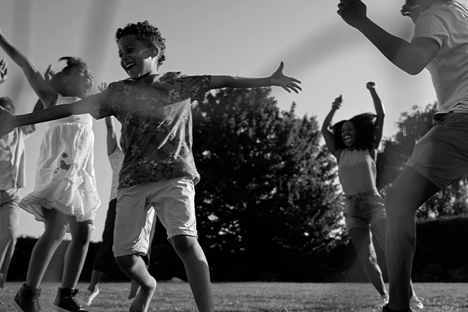 Foto em preto e branco mostra várias crianças sorridentes comemorando. Representa celebração pelo aniversário do Marco Legal