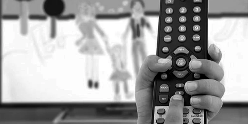 Foto em preto e branco de controle remoto em frente à TV